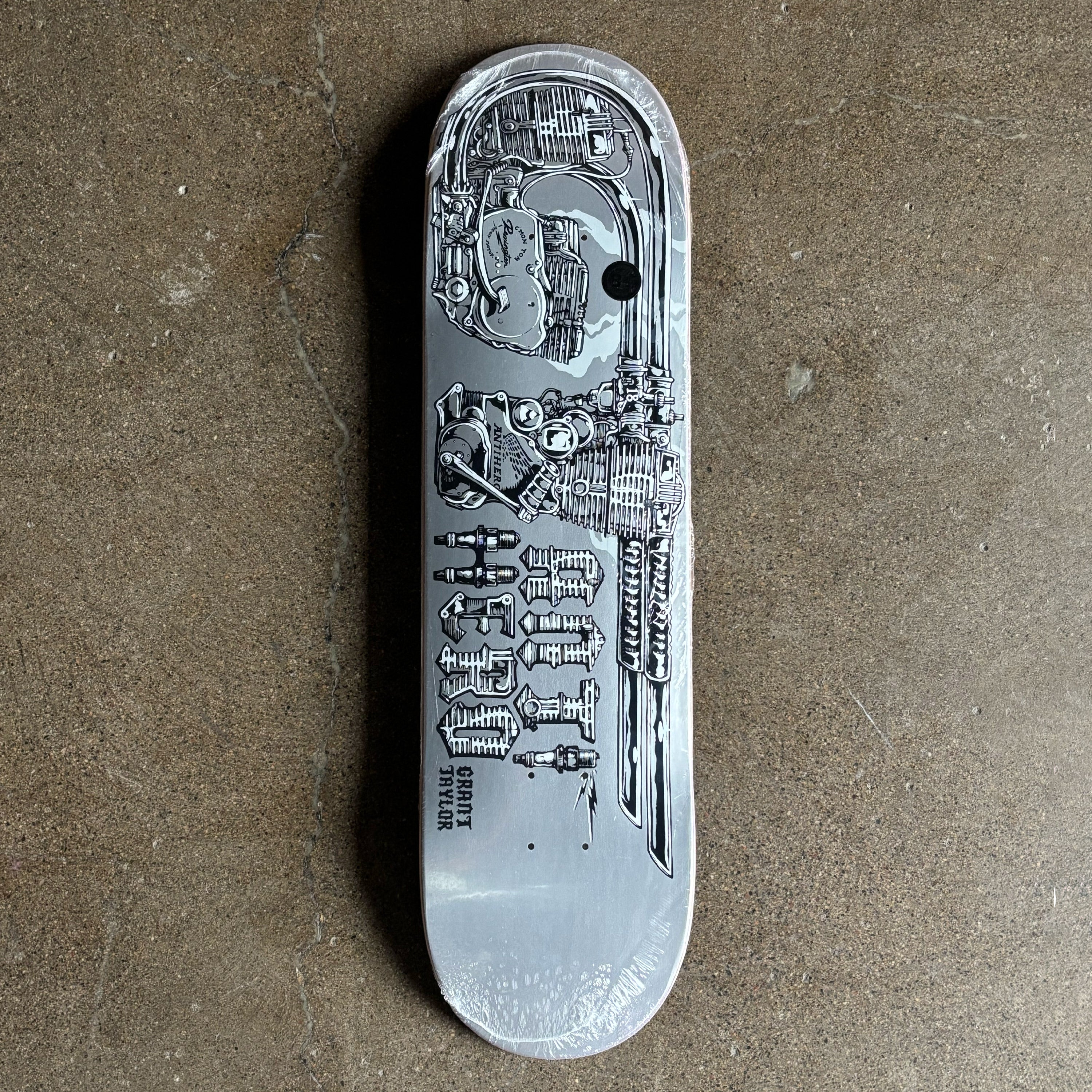 Silver skateboard deck with detailed engravings on a brown surface